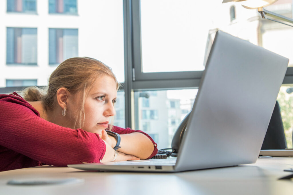 Frau sitzt abgekämpft und demotiviert vor ihrem Laptop