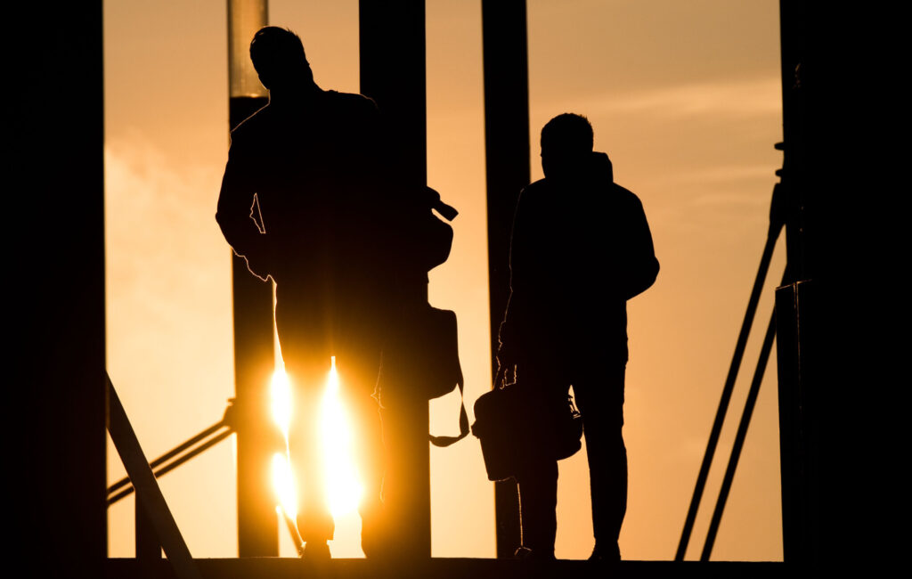 KarriereRegion Bayreuth - Zwei Männer gehen mit Aktentasche bei Sonnenaufgang über Brücke
