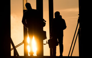 Arbeitsmarkt - KarriereRegion Bayreuth - KarriereRegion Bayreuth KarriereRegion Bayreuth - Zwei Männer gehen mit Aktentasche bei Sonnenaufgang über Brücke