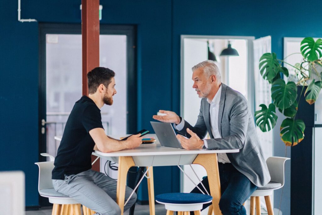 Angestellter sitzt mit Chef am Tisch